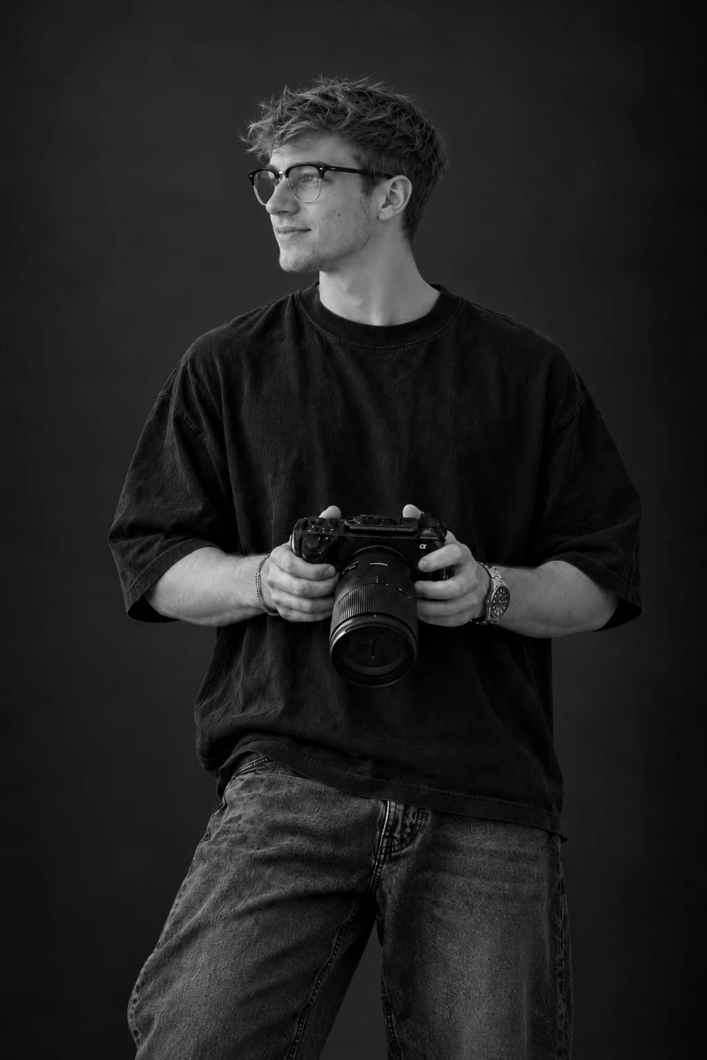 Owen holding a cinema camera, black-and-white studio portrait